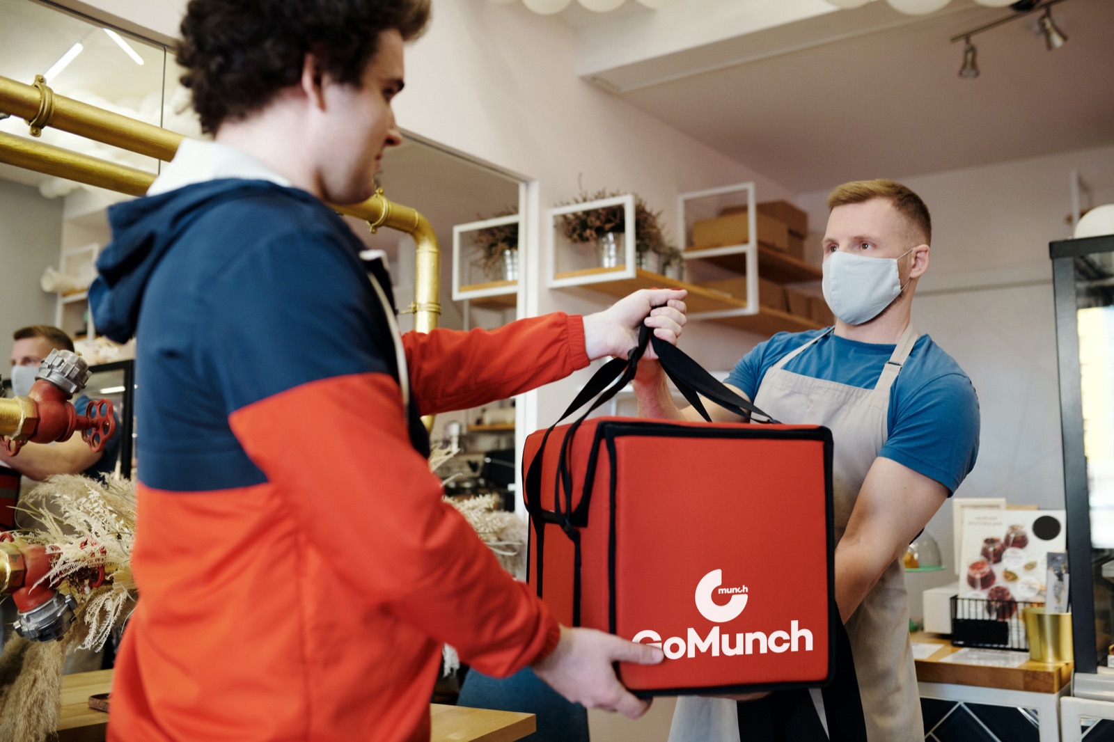 A takeaway handing over a GoMunch delivery bag